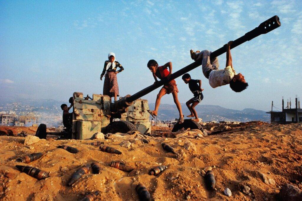 Children playing on abandoned artillery in a desert landscape